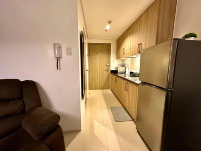 a kitchen with a stainless steel refrigerator and a couch at Luxury Seaside Sunset View at SM Mall of Asia with free parking in Manila