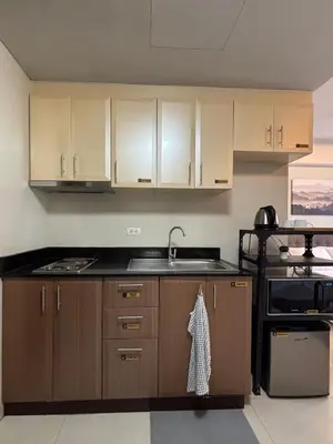 a kitchen with wooden cabinets and a sink at One Palm Tree Villas short walk via Runway Manila NAIA T3 in Manila
