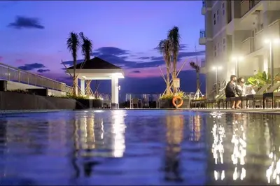 a group of people standing next to a swimming pool at night at City and Sea view Staycation at Coast Residences in Manila