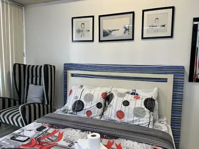a bedroom with a bed and a chair and pictures on the wall at Del's Condotel across NAIA Terminal 3 in Manila