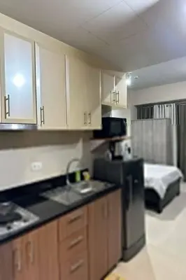 a kitchen with a sink and a refrigerator and a bed at Del's Condotel across NAIA Terminal 3 in Manila