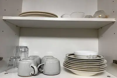 a shelf with plates and cups and dishes in a kitchen at Del's Condotel across NAIA Terminal 3 in Manila