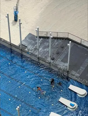 a swimming pool next to a beach with two swimmers at Azure south urban beach resort near airport in Manila