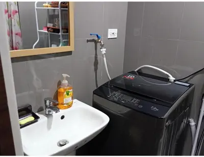 a bathroom with a sink and a washing machine at Marivic's Place at Air Residences Makati in Manila
