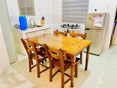 a kitchen with a wooden table with chairs and a refrigerator at Awesome 2 bedrooms, living & dining area in General Trias