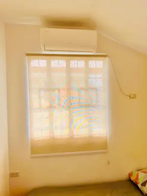 a window in the corner of a room with a blind at Awesome 2 bedrooms, living & dining area in General Trias