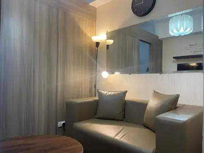 a living room with a couch and a mirror and a clock at Staycation Mandaluyong Fame residences greenfield district by darpm in Manila