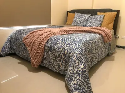 a bed with a blanket and pillows on it at Best Value Q Condo Radiance29S near Airport, Casinos, Star City, MOA, PICC, Harbour Square, Dolomite Beach in Manila
