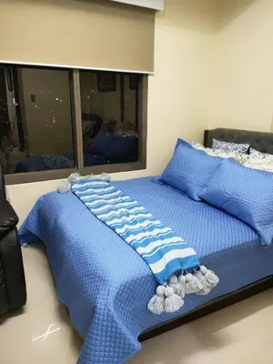 a bed with a blue blanket and pillows on it at Best Value Q Condo Radiance29S near Airport, Casinos, Star City, MOA, PICC, Harbour Square, Dolomite Beach in Manila