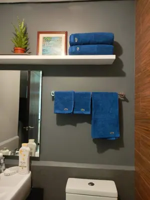 a bathroom with blue towels and a sink and a mirror at Best Value Q Condo Radiance29S near Airport, Casinos, Star City, MOA, PICC, Harbour Square, Dolomite Beach in Manila