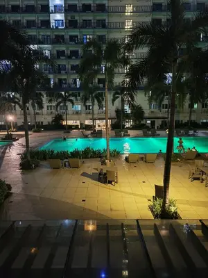 a large swimming pool with palm trees and a building at Amigo's Place at Sea Residences in Manila