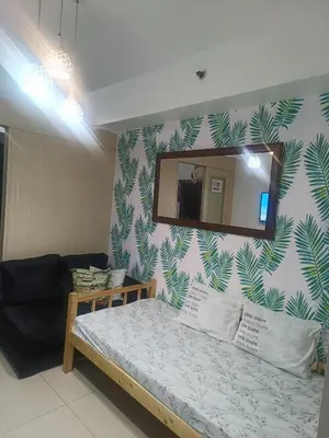 a bedroom with a bed with a mirror and a couch at Amigo's Place at Sea Residences in Manila