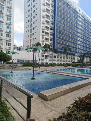 a swimming pool with umbrellas in front of a building at Amigo's Place at Sea Residences in Manila