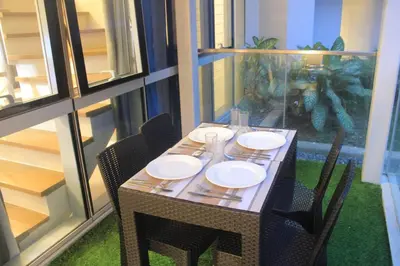 a table with chairs and plates on it in a balcony at A2J Luxury 3BR Suite Near Uptown Mall BGC Taguig in Manila