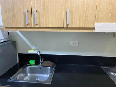 a kitchen counter with a sink and wooden cabinets at SHELL RESIDENCE C10 SHORWALK TO MALL OF ASIA NEAR AIRPORT in Manila