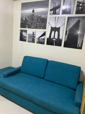 a blue couch in a room with pictures on the wall at SHELL RESIDENCE C10 SHORWALK TO MALL OF ASIA NEAR AIRPORT in Manila