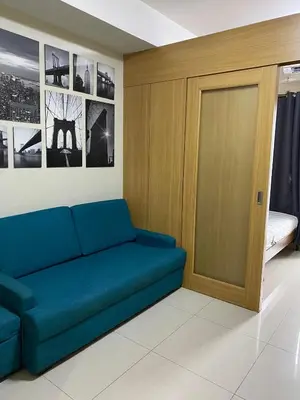 a living room with a blue couch and a door at SHELL RESIDENCE C10 SHORWALK TO MALL OF ASIA NEAR AIRPORT in Manila