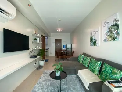 a living room with a couch and a flat screen tv at Family size Staycation in Makati with new year's firework balcony view in Manila