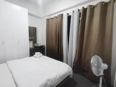 a bedroom with a bed and a fan and curtains at Accommodation services in Manila