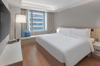 a bedroom with a large white bed and a window at Lanson Place Mall of Asia Manila in Manila