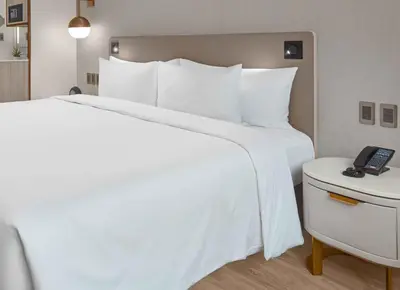a hotel room with a white bed and a telephone at Lanson Place Mall of Asia Manila in Manila