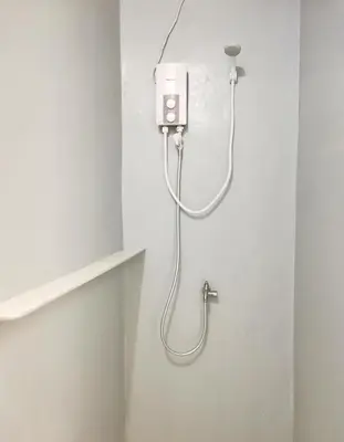 a shower in the corner of a bathroom at NomadsMNL Airport Hostel in Manila