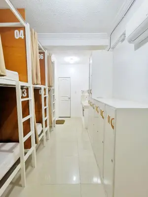 a dorm room with bunk beds and a hallway at NomadsMNL Airport Hostel in Manila