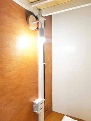 a wall mounted light in a room with a door at NomadsMNL Airport Hostel in Manila