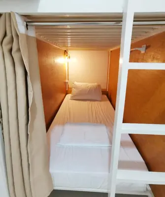 a bunk bed in a room with a ladder at NomadsMNL Airport Hostel in Manila