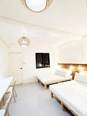 a white room with two beds and a tv at NomadsMNL Airport Hostel in Manila
