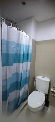 a bathroom with a toilet and a shower curtain at Shore Residence Tower C2 in Manila