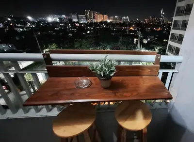a wooden bench on a balcony with a view of the city at Stylish 1BR with Wifi and Queen size bed in Grace Res in Manila