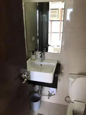 a bathroom with a sink and a toilet and a mirror at Casa Antonio at Viceroy McKinley Hill in Manila