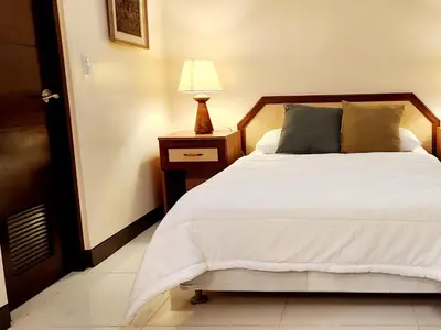 a bedroom with a bed and a lamp on a night stand at Casa Antonio at Viceroy McKinley Hill in Manila