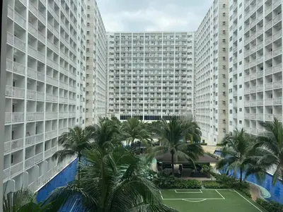 a view of a large building with palm trees and a tennis court at SHORE RESIDENCE D9 Shortwalk Mall of Asia Near Airport in Manila