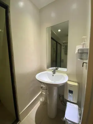 a bathroom with a white sink and a mirror at South of Market Private Residence in Manila