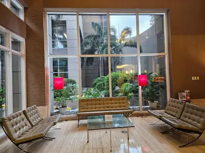 a living room with two chairs and a couch and a large window at South of Market Private Residence in Manila