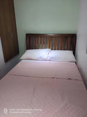 a bedroom with a bed with a wooden headboard at Fort Victoria Condominium Tower C in Manila