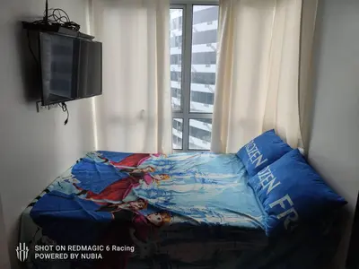 a bed in a room next to a window at Fort Victoria Condominium Tower C in Manila