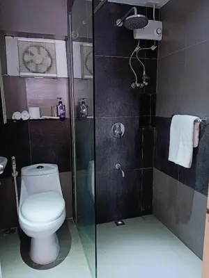 a bathroom with a toilet and a glass shower at Fort Victoria Condominium Tower C in Manila