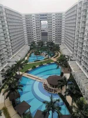 an aerial view of a resort with a pool and palm trees at Jam Staycation at Shell Residences in Manila