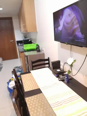 a dining room with a table and a television on the wall at Jam Staycation at Shell Residences in Manila
