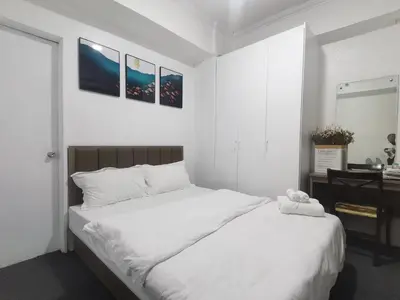 a bedroom with a large white bed and a desk at Comfort Accommodation Services in Manila