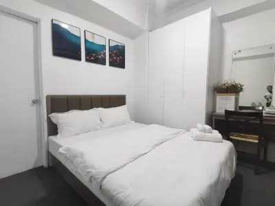 a bedroom with a large white bed and a desk at Comfort Accommodation Services in Manila