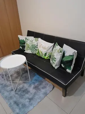 a black couch with pillows and a table on a rug at Jamaica's Place 1br Amenities View at Shell Residences in Manila