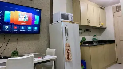 a kitchen with a refrigerator and a tv on the wall at CHATEAU ELYSEE a8 near Airport and Sm mall, WIFI in Manila