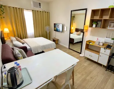a room with a living room with a bed and a mirror at Hannah’s Morning Sun - Studio Room in Manila