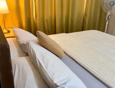 a bed with two pillows on it with a fan at Hannah’s Morning Sun - Studio Room in Manila