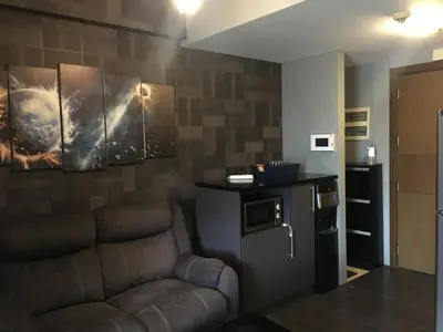a living room with a couch and a refrigerator at Cozy Condo Near NAIA with WIFI, Pool and Balcony in Manila