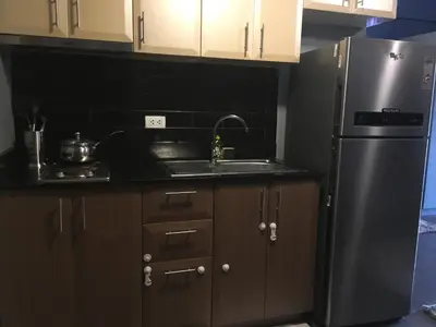 a kitchen with brown cabinets and a stainless steel refrigerator at Cozy Condo Near NAIA with WIFI, Pool and Balcony in Manila